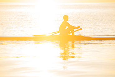 Silhouette of Caucasian man rowing on lake