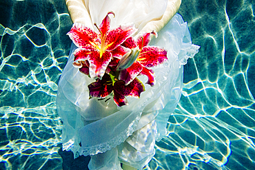 Caucasian woman wearing dress holding bouquet of flowers underwater