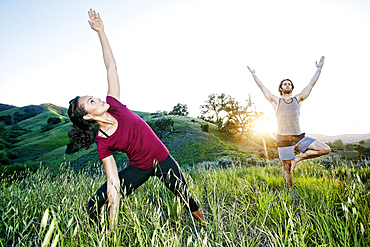 Couple practicing yoga on hill