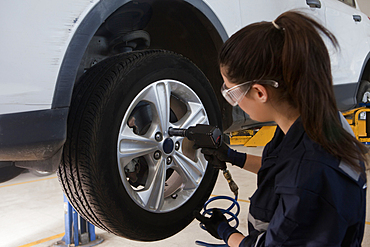 Hispanic mechanic repairing car wheel