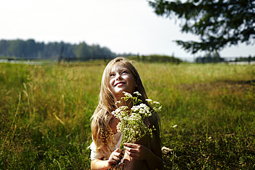 Caucasian girl holding bouquet of wildflowers in field