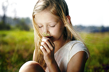 Caucasian girl smelling wildflower in field