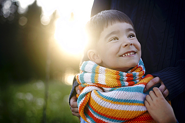 Caucasian woman holding shoulders of boy wearing multicolor scarf