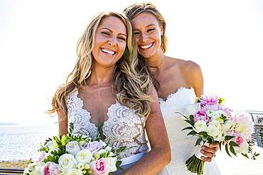 Smiling Caucasian brides holding bouquets