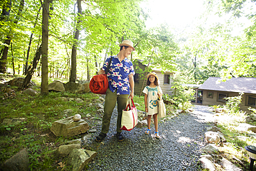 Caucasian father and daughter carrying bags at cabin