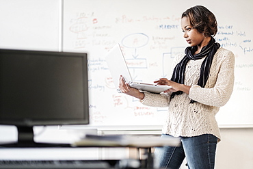 Black businesswoman using laptop near whiteboard