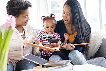 Black multi-generation family looking at photo album