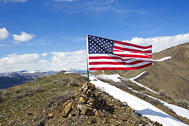 American flag waving from pile of rocks on mountain