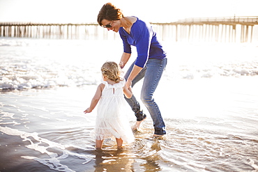 Caucasian mother and daughter walking on beach