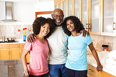 Black family hugging in kitchen