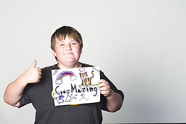 Boy holding sign gesturing thumbs-up