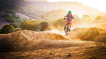 Mixed race boy riding dirt bike on track