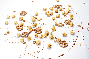 Chocolate, caramel popcorn and pretzels on white background