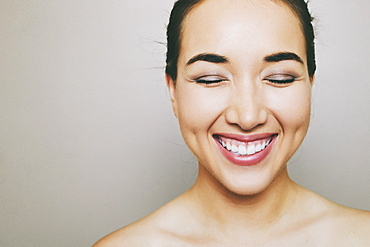 Portrait of laughing naked Hispanic woman with eyes closed