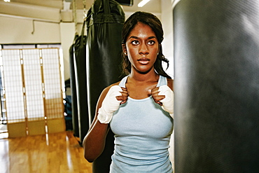 Black woman staring at heavy bag in gymnasium