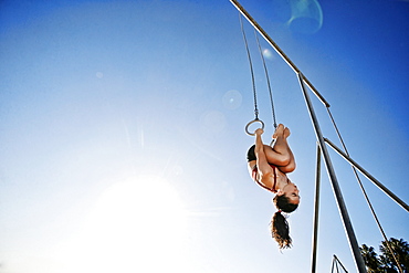 Caucasian woman using gymnastic rings at beach