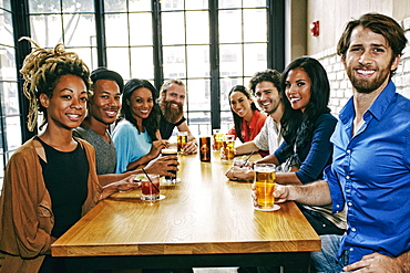 Smiling friends posing at table in bar