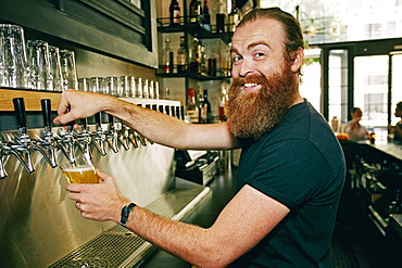 Smiling Caucasian bartender pouring beer