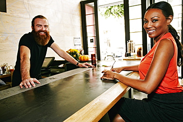 Smiling bartender and customer at bar