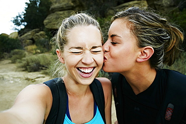 Woman kissing cheek of friend outdoors