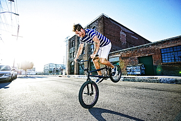 Caucasian man riding BMX bike on street