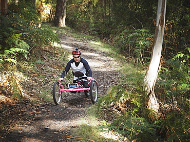 Man riding modified bicycles on forest path