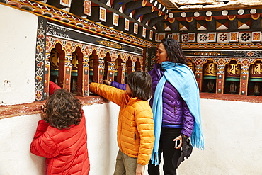 Mixed Race mother and sons spinning prayer wheels