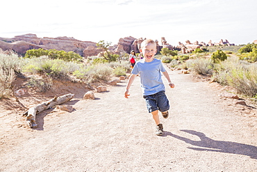 Caucasian boy running on dirt path