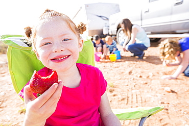 Caucasian girl eating strawberry while camping