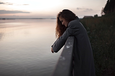 Caucasian woman leaning over river wall