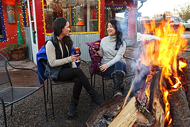 Women drinking cocktails outdoors at storefront campfire