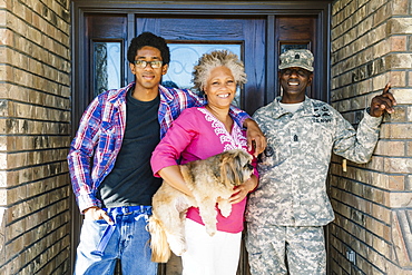 Black family posing with dog in doorway