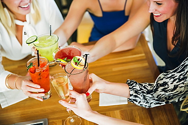 Caucasian women toasting at bar with cocktails