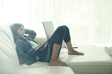 Mixed Race girl using laptop on sofa