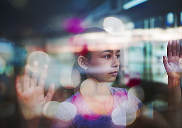 Mixed race girl looking out window