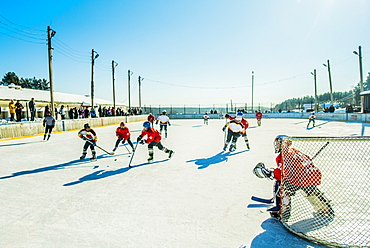 Caucasian boys playing ice hockey outdoors