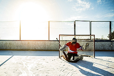 Caucasian boy playing goalie in ice hockey outdoors