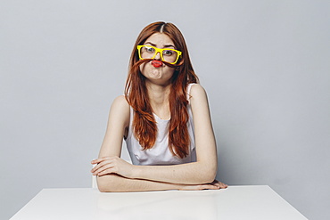 Caucasian woman sitting at table making a mustache with hair