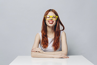 Caucasian woman sitting at table with tongue out