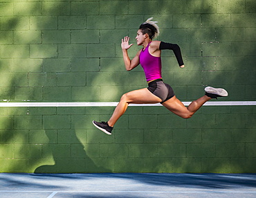 Athletic woman with prosthetic arm running against wall