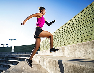 Athletic woman with amputated hand running up steps