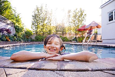 Portrait of smiling boy (10-11) in backyard swimming pool