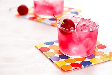 Red mocktail with cherry on colorful napkin