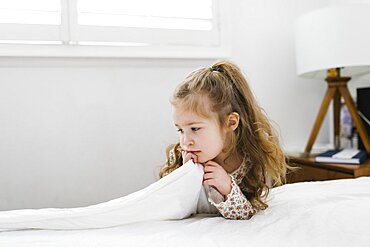 Pensive girl (2-3) leaning on bed