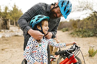 Father adjusting daughters (8-9) helmet