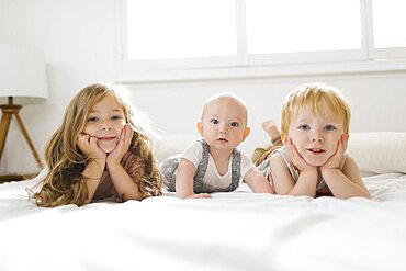 Portrait of siblings (6-11 months, 2-3) lying on bed