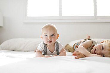 Portrait of brothers (6-11 months, 2-3) lying on bed