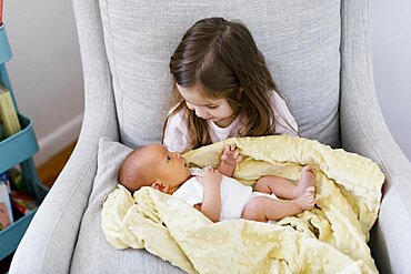 Girl (2-3) holding newborn baby brother (0-1 months)