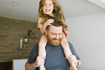 Father carrying daughter (2-3) on shoulders