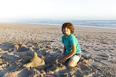 South Africa, Hermanus, Boy (8-9) building sand castle on Grotto Beach